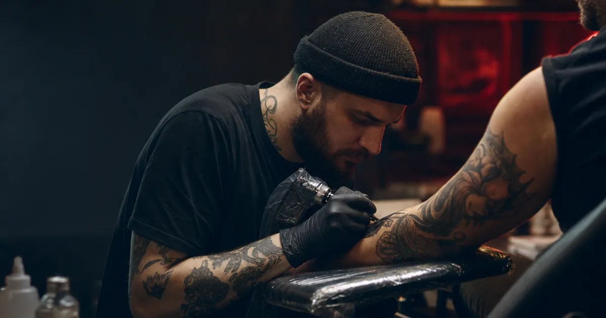 Tattoo artist working on a detailed arm tattoo in a professional studio